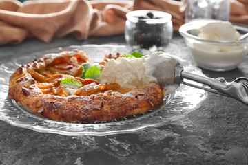 Plate with delicious peach galette and ice-cream on grunge table