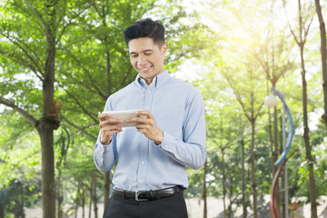 Smiling asian businessman with tablet walking