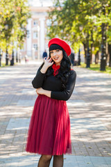 beautiful girl in a red beret and a red skirt for a walk in the city. French style in clothes. Romantic girl