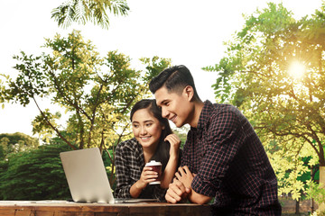 Attractive asian couple watching media on laptop