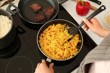 Woman cooking rice on stove in kitchen, closeup