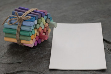 Pastel crayons and white watercolor paper on dark stone background. Copy space. Selective focus