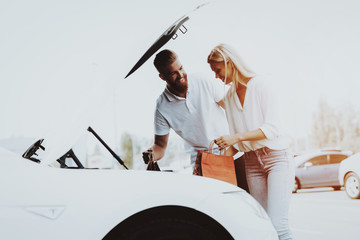 Man And Woman Putting A Bag In Tank Of Tesla Car.
