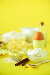Healthy baking ingredients - butter, sugar, flour, eggs, oil, spoon, rolling pin milk over yellow background. Banner. Bakery food frame, cooking concept. Copy space.