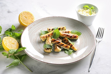 Plate with tasty grilled zucchini on light table