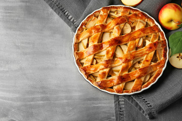 Dish with delicious apple pie on grey table