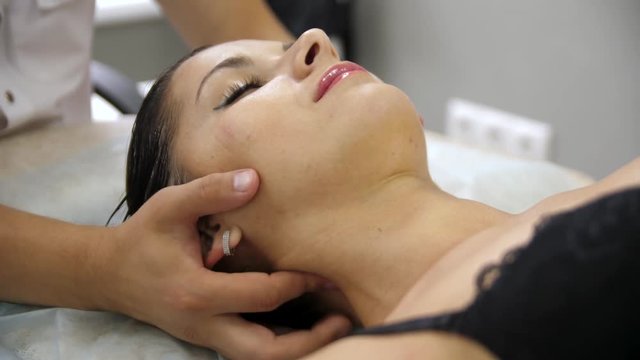 Woman doing neck massage at the reception of the chiropractor. Girl smiles with pleasure during the massage.