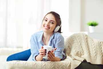 Girl in headphones smiling listening to music sitting in the room.