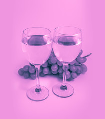 Rose in a two wine glasses, grape on the background. Romantic date, vine tasting concept.