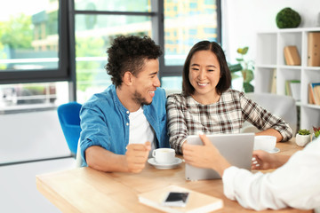 Happy interracial couple with real estate agent in office