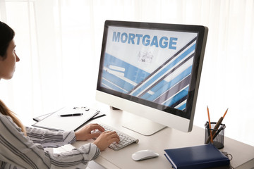 Woman using computer to pay mortgage loan online in office