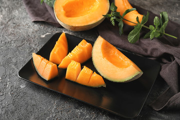 Plate with tasty cut melon on table