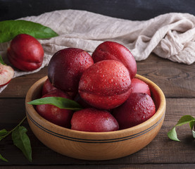 ripe red peaches in a wooden bowl on a table