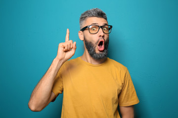 Portrait of emotional man with raised index finger on color background