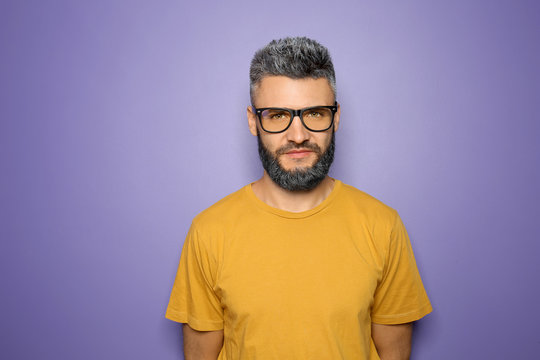 Portrait of handsome man with dyed hair and beard on color background