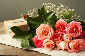 Beautiful roses with gift box on wooden table