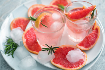 Fresh grapefruit cocktail with rosemary in glasses on plates