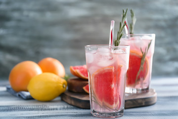Fresh grapefruit cocktail with rosemary in glasses on wooden table
