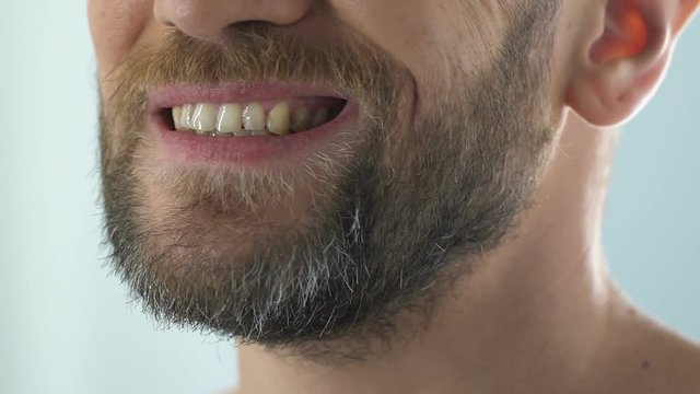 Bearded man looking at teeth in mirror, suffering gum infection pulpitis disease