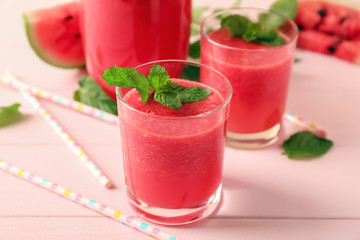 Glasses with fresh watermelon smoothie on color table