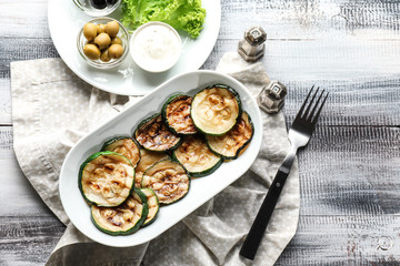 Plate with tasty grilled zucchini on wooden table