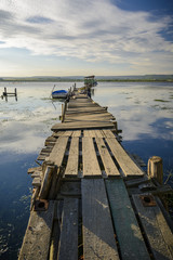Wooden pier on a lake with a fishing hut. sunset with calm water.