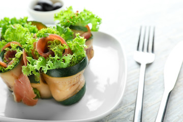 Tasty zucchini rolls with prosciutto on plate
