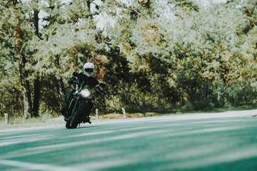 Biker In Helmet Is Riding On Highway In A Forest.