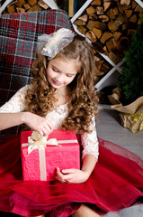 Adorable smiling little girl in princess dress holding gift box in christmas time