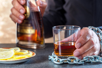 Hand of male chained to glass of alcohol drink.Alcohol dependence.Problem alcoholism in society.