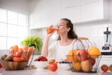Poster de jardin Jus Healthy young woman in a kitchen with fruits and vegetables and juice