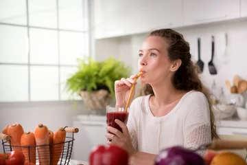 Cercles muraux Jus Healthy young woman in a kitchen with fruits and vegetables and juice