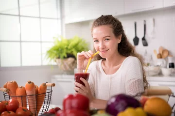 Photo sur Plexiglas Jus Jeune femme en bonne santé dans une cuisine avec fruits et légumes et jus