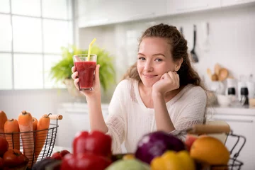 Crédence de cuisine en verre imprimé Jus Jeune femme en bonne santé dans une cuisine avec fruits et légumes et jus