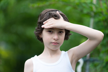 Portrait of a boy in a sleeveless shirt on a nature background. Country style.
