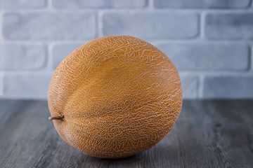 Ripe yellow melon on gray wooden table.