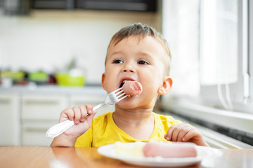 child in the kitchen eating sausage and mashed potatoes