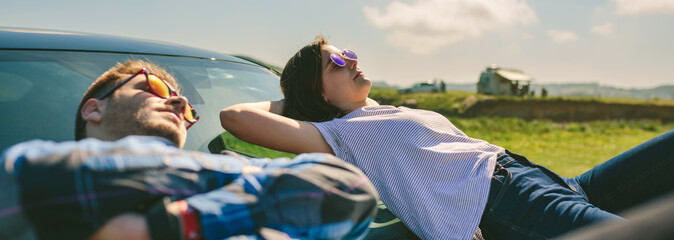 Young couple resting lying on the windshield and the hood of the car © David Pereiras