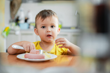 child in the kitchen eating sausage and mashed potatoes