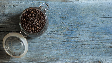 Coffee bean in glass jar on wooden table.