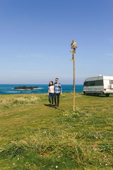 Young couple taking a walk near the coast with a camper in the background