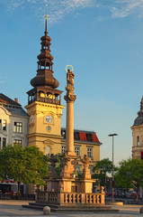 Ancient column with figure of Virgin Mary and Ostrava Museum building in Old Town Hall at Masaryk Square in Ostrava. Summer evening view
