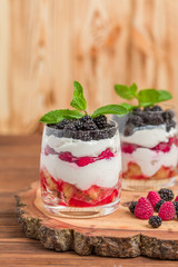 Trifle close up photography with fresh multi layered dessert with dairy and ripe raspberries and blackberries.
