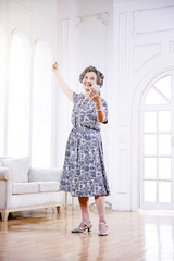 Asian grandmother with headphones listening to music dancing indoors