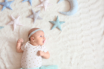 Cute little baby with toys lying on bed, top view