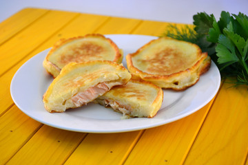 pancakes with fish on a white plate on a yellow background
