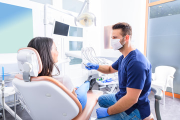 Młody dentysta leczy pacjentkę w gabinecie stomatologicznym - 222135901