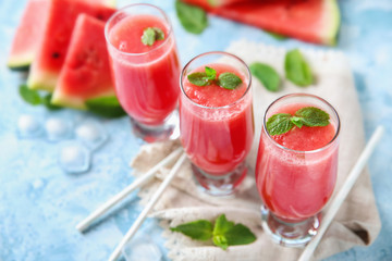Glasses with fresh watermelon smoothie on color table