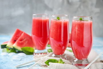 Glasses with fresh watermelon smoothie on color table