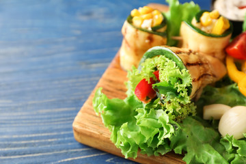 Tasty zucchini roll with vegetables on wooden board